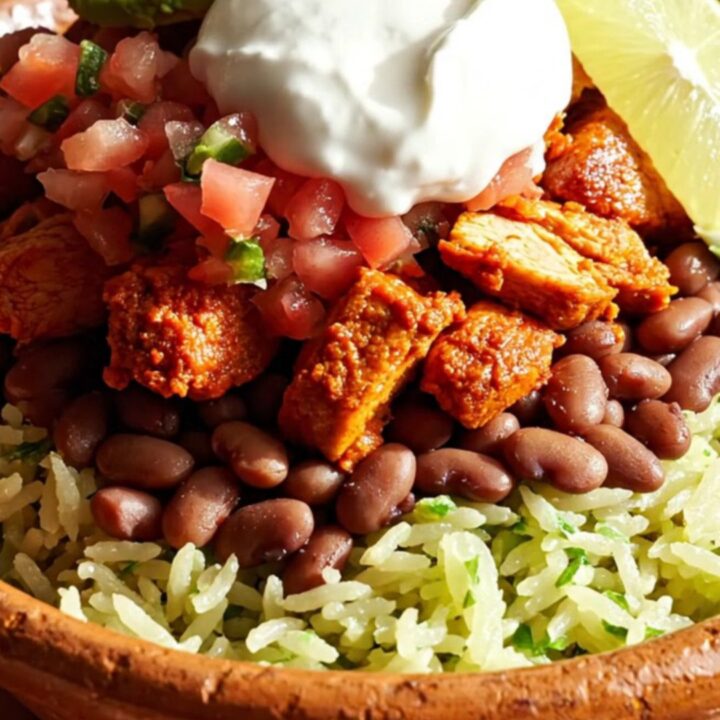 A vibrant burrito bowl featuring tender, achiote-glazed chicken topped with melted Chihuahua cheese, served with rice, beans