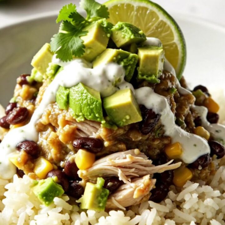 A steaming bowl of cilantro lime chicken burrito bowls topped with melted cheese, avocado, and sour cream.