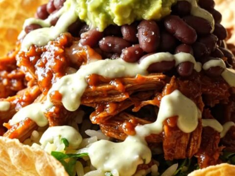 A close-up of a bowl filled with sweet shredded pork topped with melted Monterey Jack cheese and fresh cilantro.
