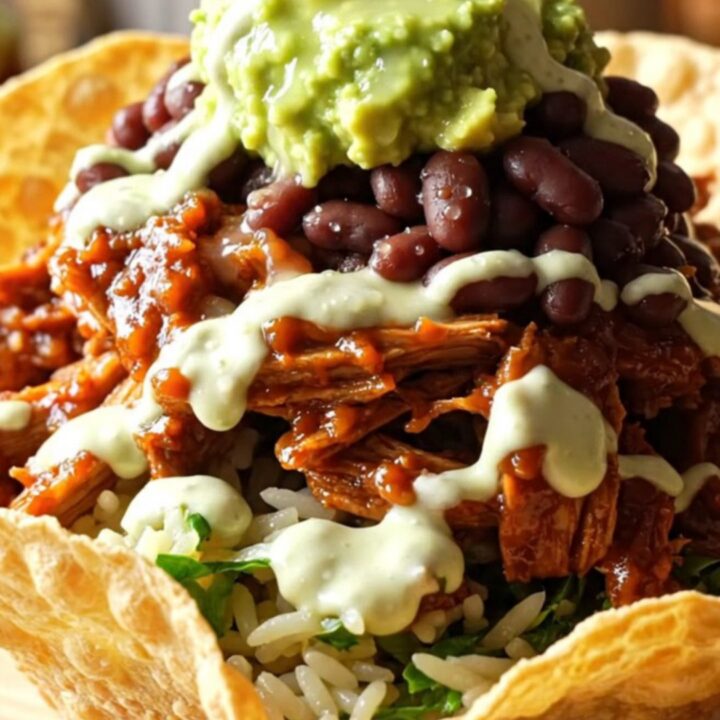 A close-up of a bowl filled with sweet shredded pork topped with melted Monterey Jack cheese and fresh cilantro.