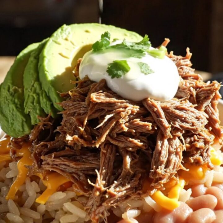 A vibrant burrito bowl featuring tender shredded beef machaca, Spanish rice, and fresh avocado.