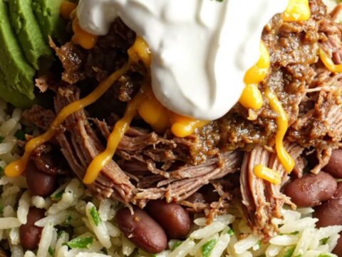A close-up of a slow cooker filled with shredded beef brisket and melted cheese, with steam rising.