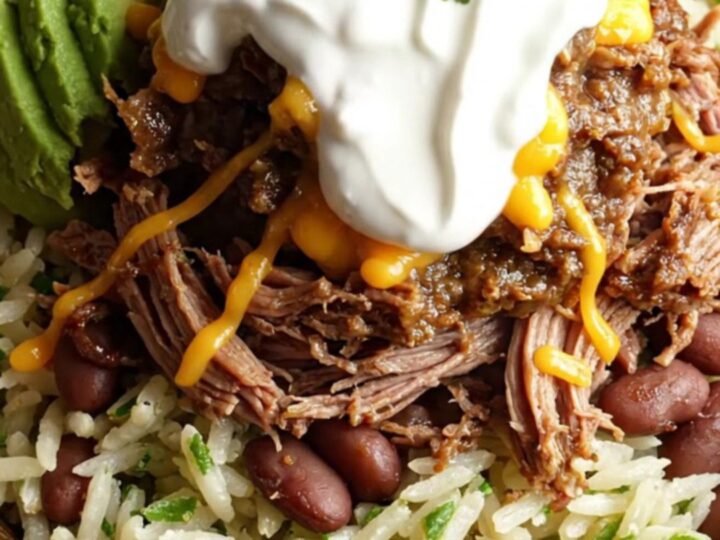 A close-up of a slow cooker filled with shredded beef brisket and melted cheese, with steam rising.