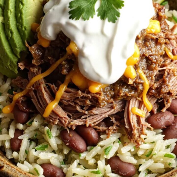 A close-up of a slow cooker filled with shredded beef brisket and melted cheese, with steam rising.