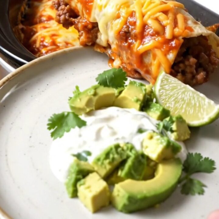 A row of beef and bean burritos in a slow cooker, smothered in red and green sauce with melted cheese.