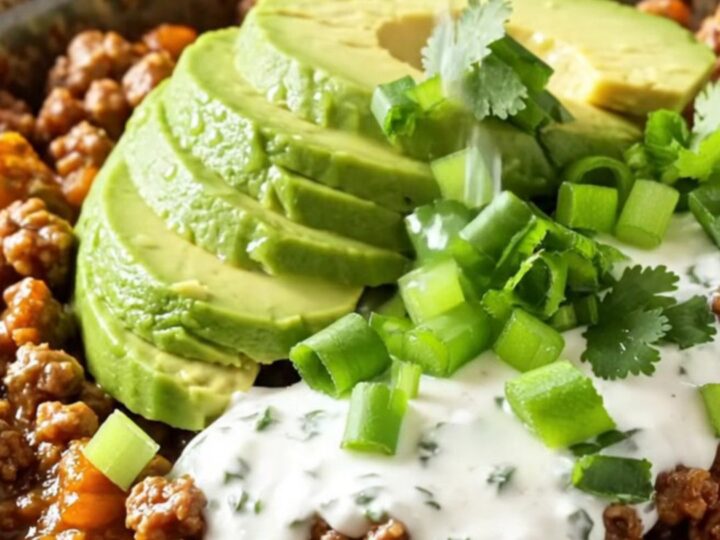 A close-up of the finished cheesy taco beef and potato hash in a matte black slow cooker.