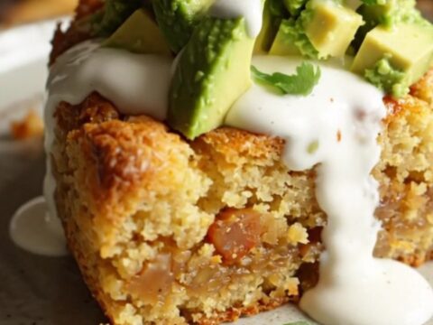 A rustic slow cooker filled with a golden, cheesy cornbread bake topped with fresh jalapeño slices and melted cheddar.