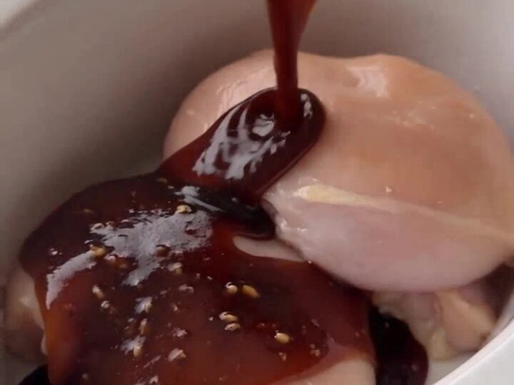 Pouring honey garlic sauce over chicken thighs in a slow cooker